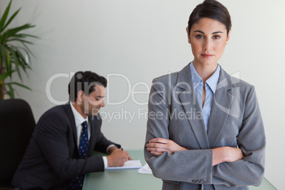 Professional businesswoman posing while her colleague is working