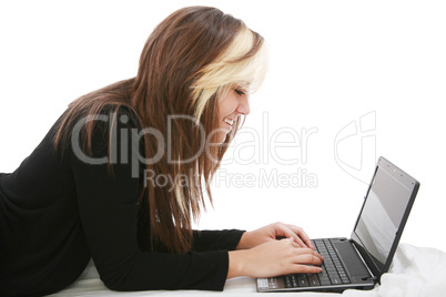 Beautiful girl relaxing on the bed with her laptop