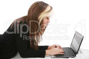 Beautiful girl relaxing on the bed with her laptop