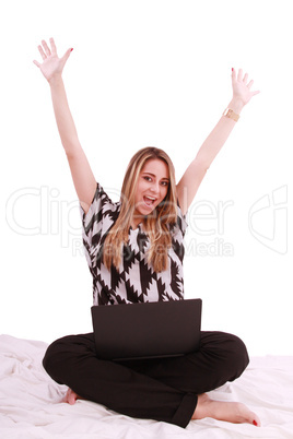 Woman sitting on the bed with a laptop computer and arms up - is