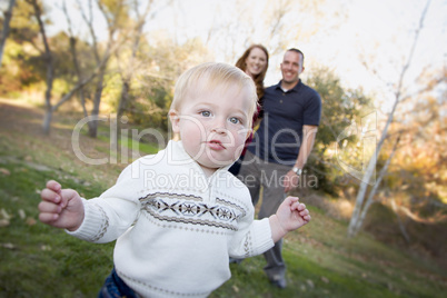 Cute Young Boy Walking as Parents Look On From Behind