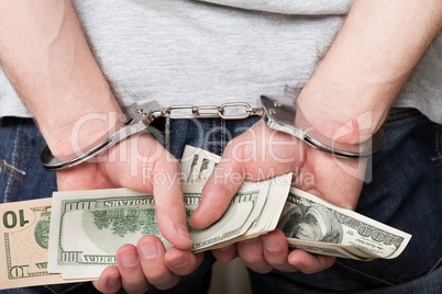 Handcuffs on hands holding money