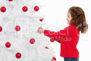 little girl decorating a christmas tree