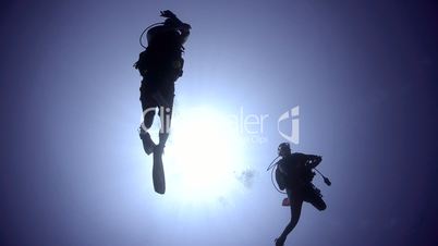 Silhouette view of two adult scuba divers