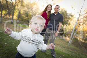 Cute Young Boy Walking as Parents Look On From Behind