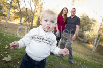 Cute Young Boy Walking as Parents Look On From Behind
