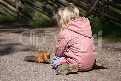 little girl plays with the squirrel