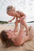 Mum with daughter play on beach
