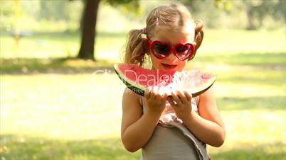 little girl with sunglasses eat watermelon