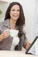 Woman Using Tablet Computer At Home Drinking Tea or Coffee