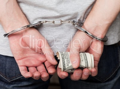 Handcuffs on hands holding money