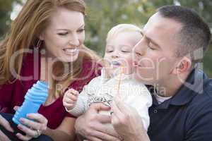 Young Parents Blowing Bubbles with their Child Boy in Park