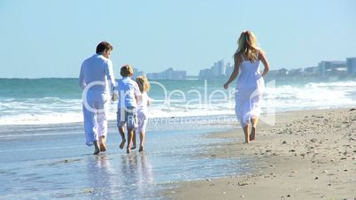 Happy Caucasian Family Walking by Ocean Shallows