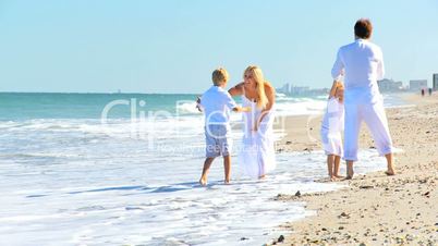 Caucasian Parents Swinging their Children on Beach