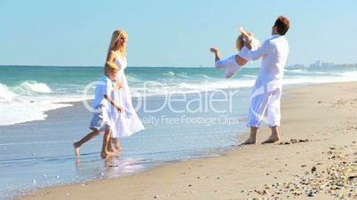 Caucasian Parents Swinging their Children on Beach
