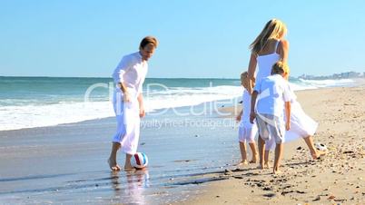 Caucasian Family Kicking a Ball on Beach