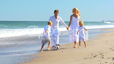 Young Family Chasing a Ball on the Beach