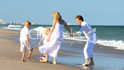 Young Family Chasing a Ball on Beach