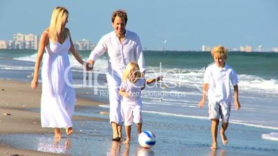 Happy Family Chasing a Ball on a Beach