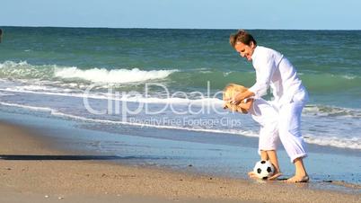 Caucasian Family Kicking a Ball on the Beach