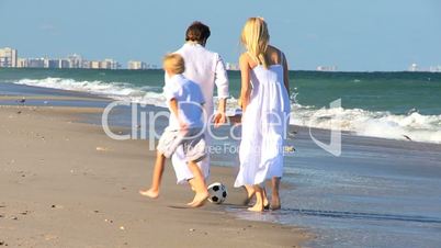 Happy Family Chasing a Ball on a Beach