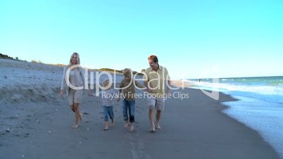 Young Caucasian Family Skipping on Beach
