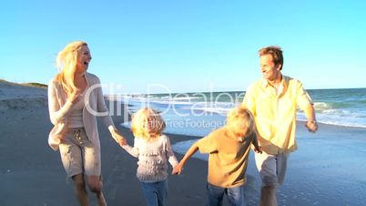 Young Caucasian Family Skipping on Beach