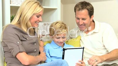 Proud Parents Watching Son Using Wireless Tablet