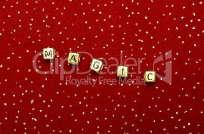 the word "magic" of beads on a red velvet with sequins