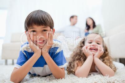 Kids lying on the carpet with parents sitting behind them