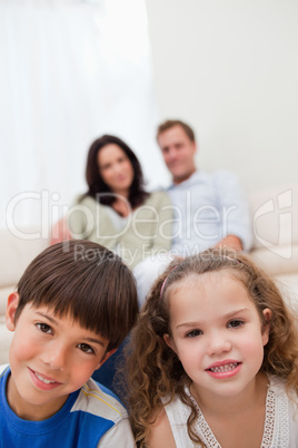 Children sitting in the living room with parents behind them