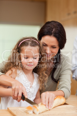 Mother and daughter cutting bread into slices