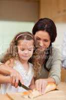 Mother and daughter cutting bread into slices