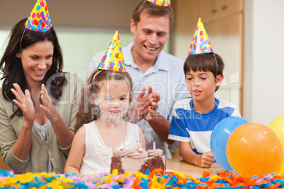 Parents applauding her daughter who just blew out the candles on