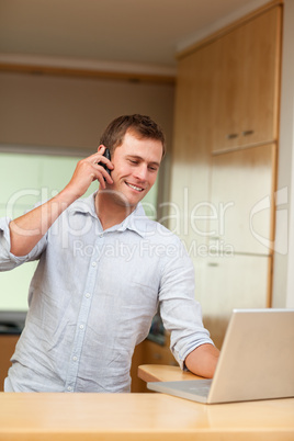 Male with cellphone and laptop in the kitchen