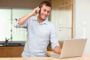 Man with cellphone and notebook in the kitchen