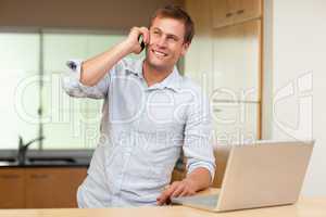 Man with laptop and cellphone in the kitchen