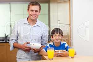 Father and son having cereals and orange juice
