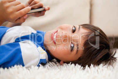 Boy lying on the carpet with cellphone