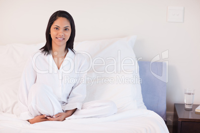 Woman in pajamas sitting on her bed