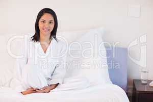 Woman in pajamas sitting on her bed