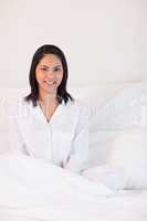 Smiling woman in pajamas sitting on the bed