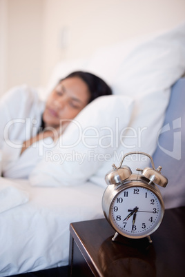 Alarm clock next to bed in which woman is sleeping