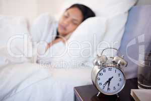 Alarm clock next to woman sleeping in her bed