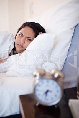 Side view of woman being annoyed by ringing alarm clock