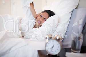 Woman covering her ears cause of ringing alarm clock