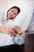 Woman getting pain in the ears by alarm clock