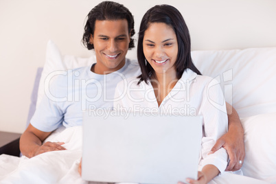 Couple sitting on the bed with their laptop