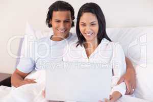Couple sitting on the bed with their laptop