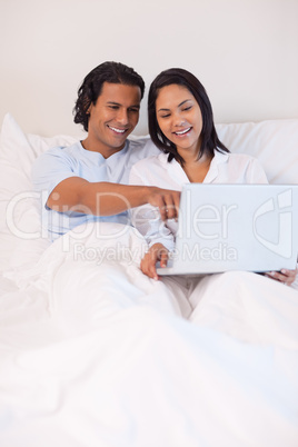 Couple sitting on the bed with their notebook